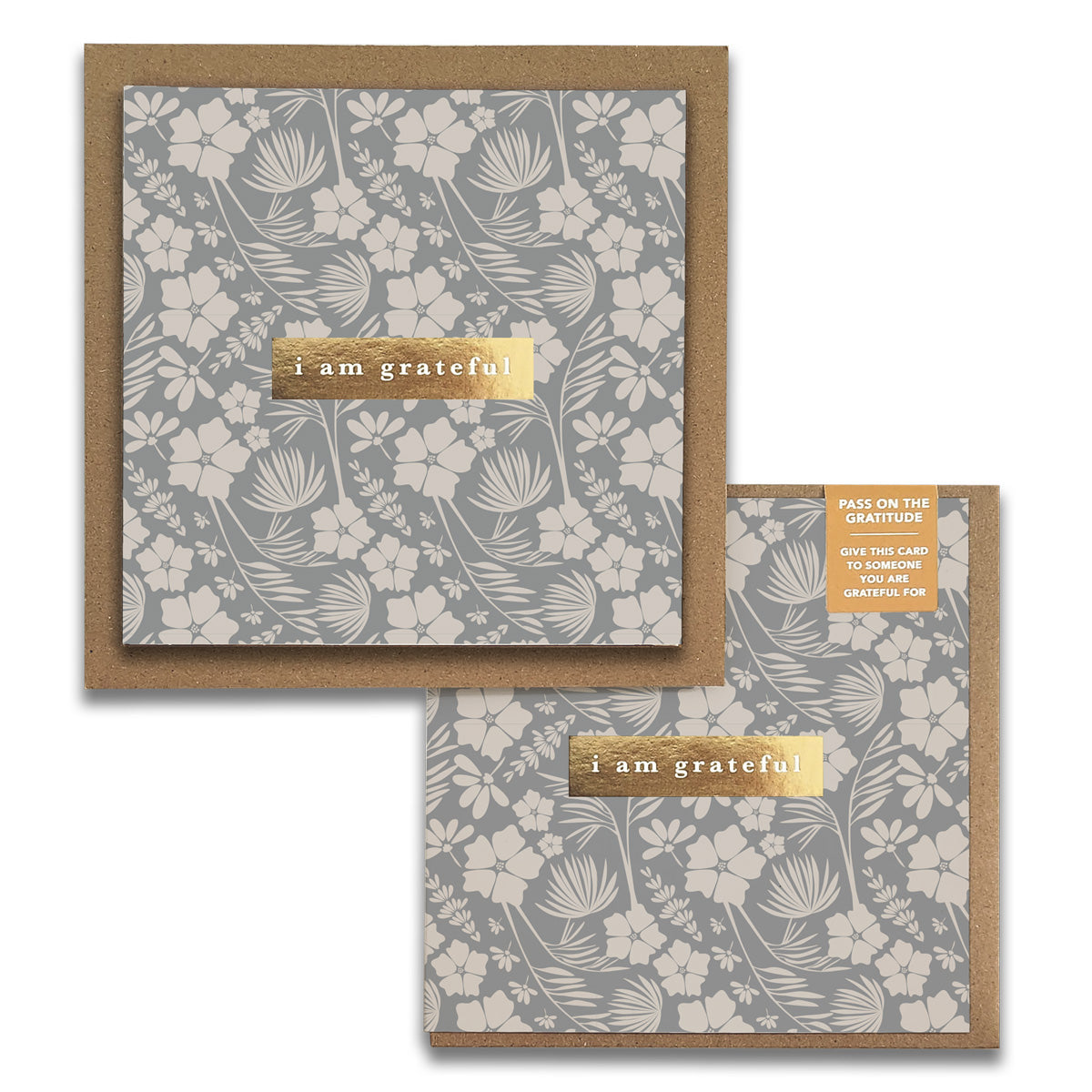 The Maylay Co. Vintage Meadow Floral Gratitude Greeting Cards feature a set of two square cards, showcasing a beige floral pattern on a gray background. Each card is elegantly embellished with a golden strip stating "I am grateful." Included is a label encouraging you to share them with someone you appreciate. These beautiful greeting cards come with brown envelopes, providing the perfect way to express your heartfelt thanks.